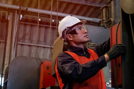 Asian worker or technician works with machine in factory.