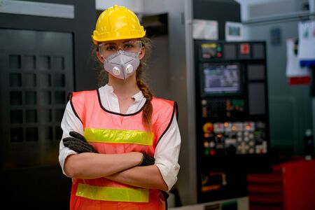 Pretty technician or worker woman with gray mask and yellow helmet stand with confident action in...