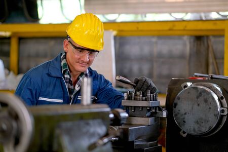 Front view of smart technician or engineer worker with protective uniform work with machine and look...