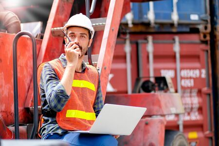 Technician or engineer worker with laptop use walkie talkie to contact with his manager in cargo shipping workplace area. Concept with good communication system help to improve better industrial.の写真素材