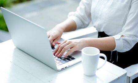 Close up woman hands are typing on keyboard of laptop with day light. Concept of work with technology equipment to communicate and motivate their business.の写真素材