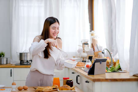 Beautiful woman show action of cooking to the tablet look like she present to friends. Concept of...