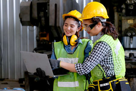 Factory worker women discuss together with laptop in workplace area. Concept of good teamwork and...