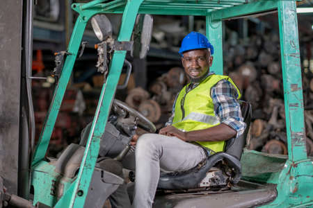 Portrait of African American factory man with smiling sit on forklift during work in workplace area...