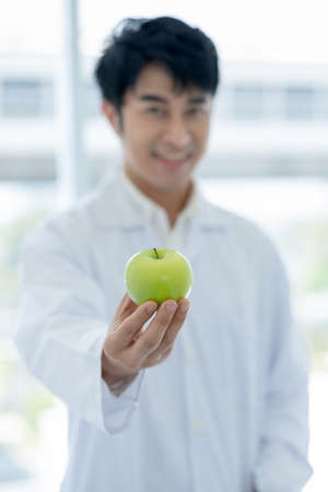 Green apple is held by smart scientist man in laboratory or classroom with concept of healthy fruit of good food for better health for people.の写真素材
