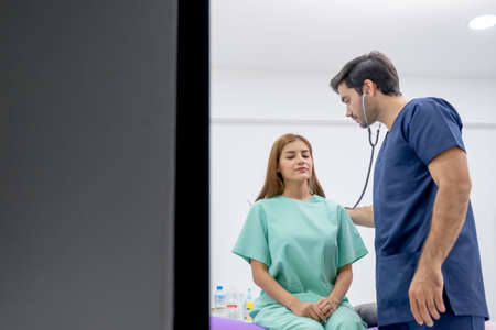 Caucasian doctor use stethoscope to analyze the symptom of Asian patient in beauty clinic or hospital.の写真素材