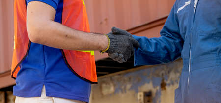 Close up hand shaking of cargo container worker or engineer in workplace area. Business Logistics import export shipping concept.の写真素材