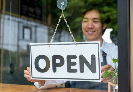 Barista or coffee maker man hold banner of open for the symbol of ready to service for customer. Concept of happy working with small business and sustainable.の写真素材