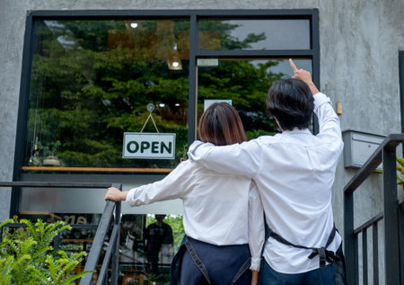 Back of couple coffee makers or coffee shop staffs that man point to the building and talk to woman....