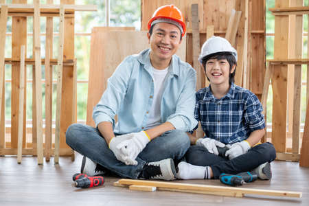 Asian father and son stay in their workplace of carpentering and look at camera with smiling. Asian...