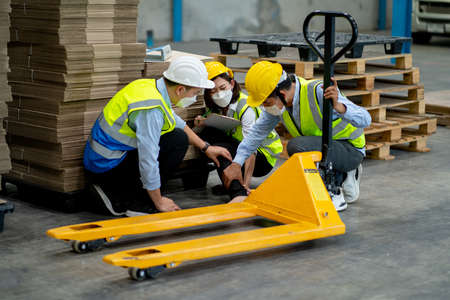 Factory worker woman was help and take care by coworker men after accident on her leg by hydraulic cart in warehouse workplace area.の写真素材
