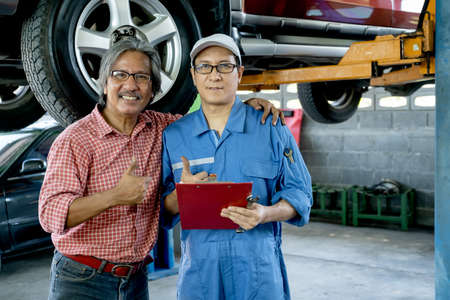 Customer heck the neck of automotive technician with smiling and look at camera also show thumbs up.の写真素材