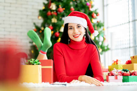 Pretty woman with Christmas costume lie on floor and look at camera with smiling stay at home with the present and Christmas tree as background.の写真素材