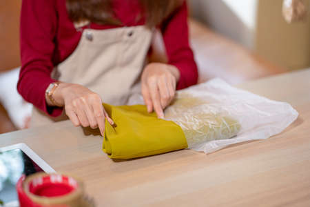 Close up hands of woman put cloth into parcel or plastic bag to prepare for online selling and delivery to customer.の写真素材