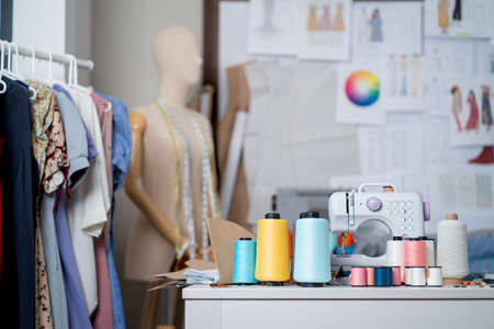 Different accessories in room of designer or tailor including clothes rack, thread spool and...