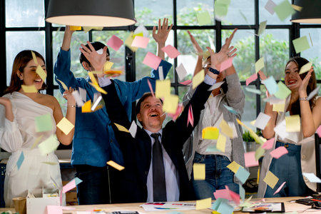 Business man and woman celebration of success work together by throw different color and small pieces of paper in office.の写真素材