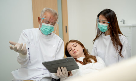 Senior dentist explain the procedure to young girl to relax during treatment process in dental clinic.の写真素材