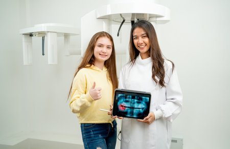 Asian dentist woman stand with young girl in front of dental x-ray machine.の写真素材