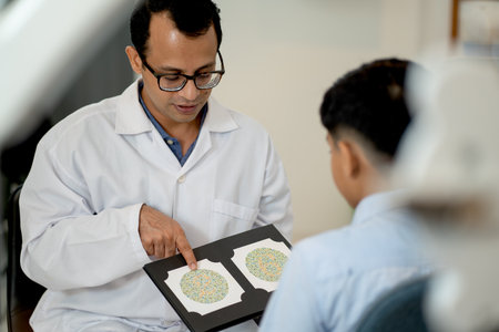 Indian optical staff point to page of book for testing color blindness to children during the process in optical shop.の写真素材