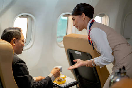 Air hostess or cabin crew serve dessert and cake to the passenger or business man.の写真素材