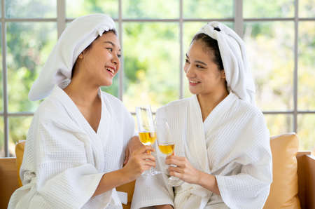 Asian woman with towel as headscarf hold glass of wine and enjoy together after finish spa and...