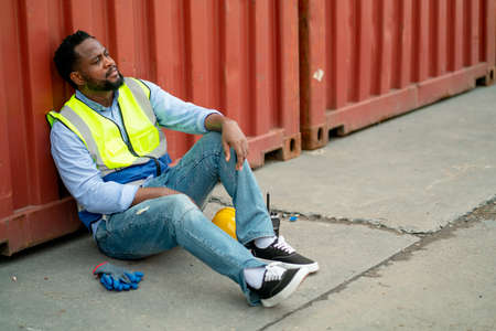 African American cargo container worker or technician sit and lean on container tank and action look like tired after work in workplace area for long time.の写真素材