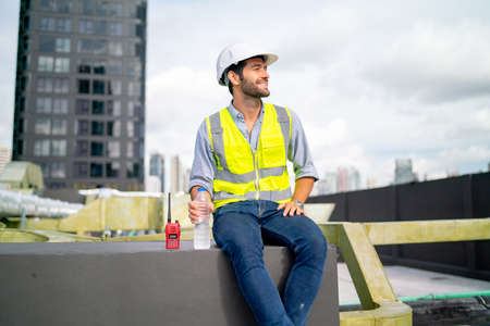 Caucasian professional engineer or technician sit on terrace of construction with relax after work and look around with happiness for success of the project.の写真素材