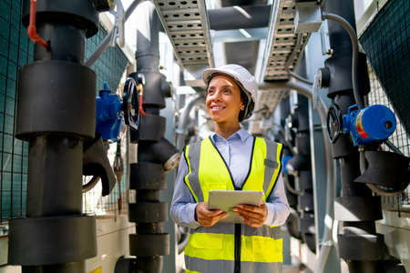 Portrait of engineer or technician worker woman stay with smiling and in area of pipe network with day light.の写真素材