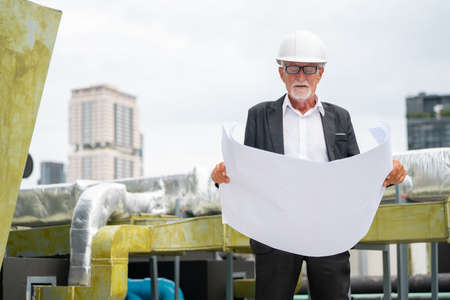 Senior professional engineer or technician use building drawing plan to guide for working in construction site.の写真素材