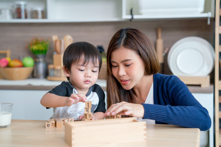 Asian mother enjoy to play wooden jigsaw puzzle together in area of kitchen of their house and they look happiness.の写真素材