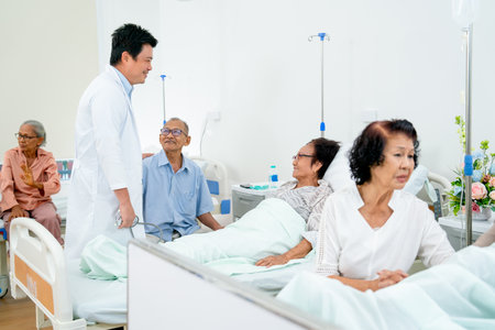 Asian doctor meet and talk with senior patient in common patient room and they look happiness during diagnosis and treatment in hospital.の写真素材