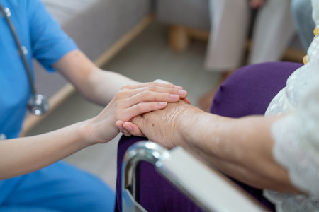 Close up hands of nurse or doctor hold senior woman hands who sit on wheelchair with concept of take care and support elderly people in clinic or hospital center.の写真素材