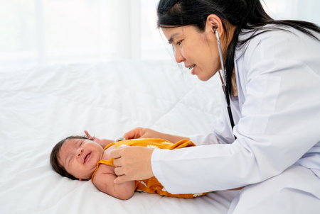 The doctor use stethoscope to check the symptom of newborn baby cry and lie on bed in room with day light.の写真素材