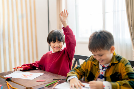 Asian boy raise his hand to ask questing in classroom and his friend look happy during work together.の写真素材