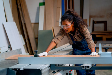 Professional carpenter woman check about cutting machine during work with wood product in workplace.の写真素材