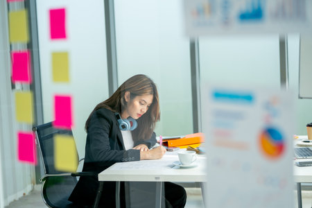 Wide shot through transparent board pretty young business woman use pen to write and note on paper...