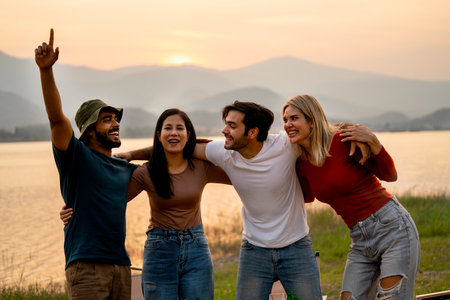 Group of friends with multi-ethnic hug together and stand in front of sunset light near lak of...