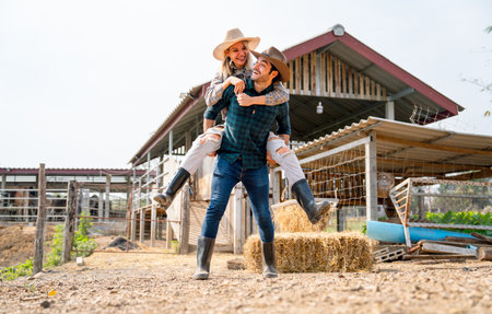 Caucasian man and woman farmer enjoy with woman riding on the back of man and go around the area of their farm with happiness and day light.の写真素材