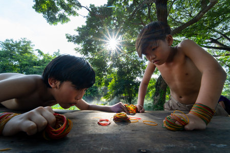 Wide angle and close up Asian boys enjoy and fun together for playing blow the rubber look like competition with traditional culture.の写真素材