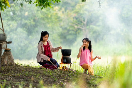 Close up Asian woman look like mother hold and prepare to cook rice near rice field and her daughter sit beside.の写真素材