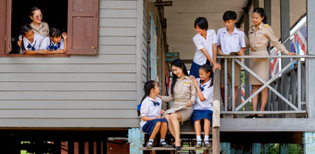 Woman teacher teach and train her student in area of steps of the building and they look happy at school.の写真素材
