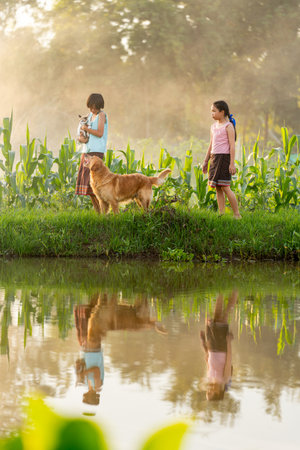 Vertical image of young Asian girl hold cat and dog also look to the cat look like want to play together and they stay near water reservior.の写真素材