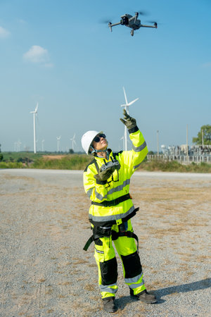 Vertical image wind turbine or windmill worker woman or technician control drone to work in...