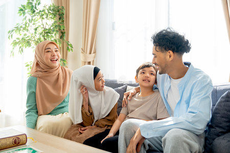 Asian muslim famity with mother, father, boy and girl stay relax together on sofa in living room of their house in concept of happy muslim family at home.の写真素材