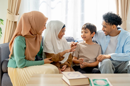 Front view of muslim child of the family enjoy to play rock-paper-scissors game together with mother and father stay beside in living room of their house.の写真素材