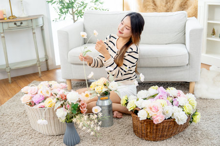 Wide shot of young Asian woman sit in living room to relax with flower arrangement in her house with day light.の写真素材