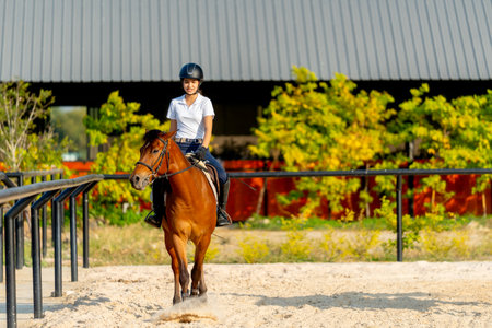 Wide shot and front view of teen girl controlling horse to walk in the arena during training or practice before competition.の写真素材