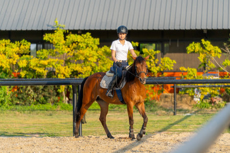 Wide shot of teen girl enjoy to ride horse for exercise and train in the horse riding arena.の写真素材