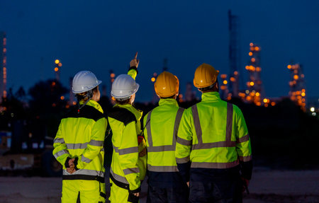 Back of group of petrochemical or gas factory stand in front of factory with show working light at night.の写真素材