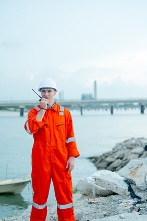 Vertical image of factory worker man use walkie talkie to contact his coworker and stay near the bay of workplace.の写真素材
